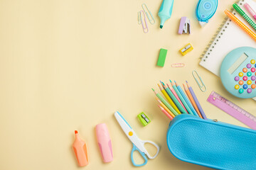 Back to school concept. Flat lay, top view colorful school supplies, blue pencil case, calculator, notepad on light yellow background.