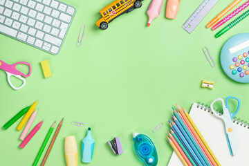 Back to school concept. Flat lay composition with Keyboard and school supplies on green background with copy space.