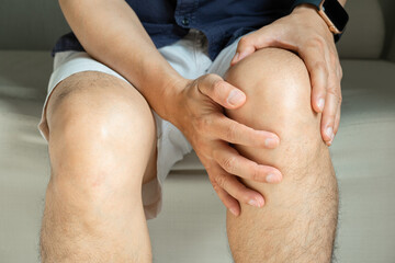 Man with knee pain, he puts his hand on his knee, pain point from osteoarthritis and...