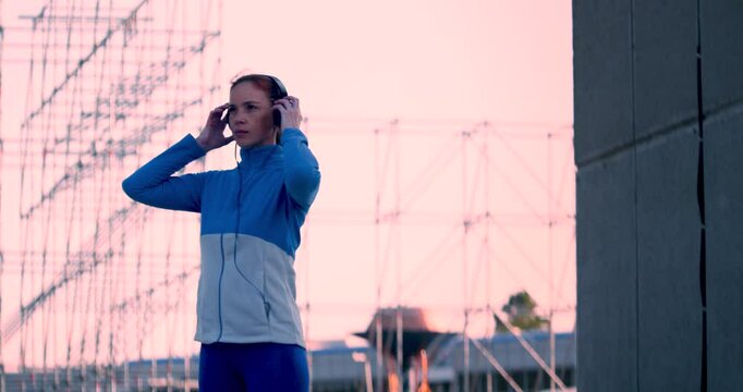 Sports in the urban rhythm of life. Middle aged sportswoman puts on headphones before morning workout. Favorite music as a motivator for your progress. Keeping your body in shape over 40.