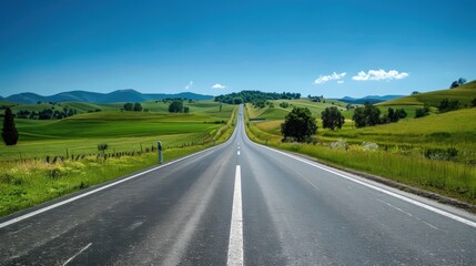 A highway stretching into the horizon, with a solid white line down the center, surrounded by a lush green countryside under a clear blue sky.