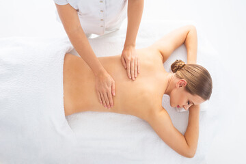 Obraz premium Young woman getting massaging treatment over white. Spa, healthcare and recreation concept.