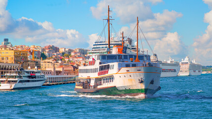 Obraz premium Cruise ship and ferry (steamboat) traffic in the Bosphorus - Sea voyage with old ferry (steamboat) on the Bosporus - Coastal cityscape with modern buildings under cloudy sky - Istanbul, Turkey 