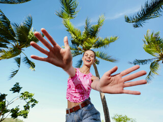 A woman catching a frisbee beneath palm trees on a sunny day with a clear blue sky