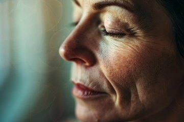 Obraz premium A close-up portrait of a mature woman with her eyes closed, meditating in a tranquil setting. Her face radiates serenity and focus as she finds inner peace