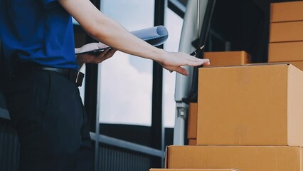 Young cheerful delivery man with parcel near car full of cardboard boxes, full length shot. Shipping service concept