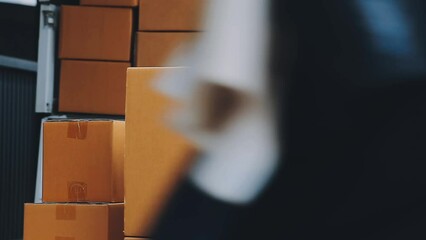 Young cheerful delivery man with parcel near car full of cardboard boxes, full length shot. Shipping service concept