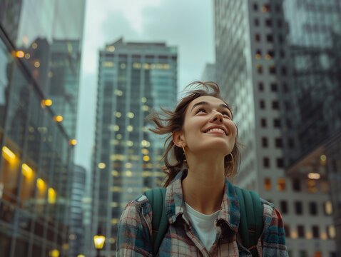 A woman with a backpack is smiling and looking up at the sky