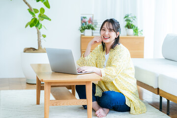 自宅でノートパソコンを操作する若い女性