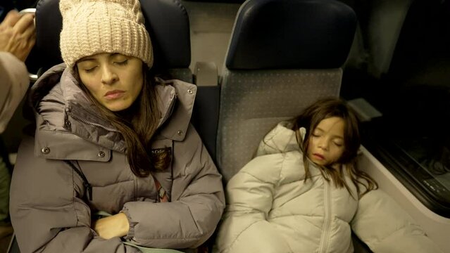 Mother And Daughter Sleeping On A Train Night Journey, Bundled In Winter Coats And Resting Peacefully In Their Seats, Creating A Serene And Cozy Travel Moment