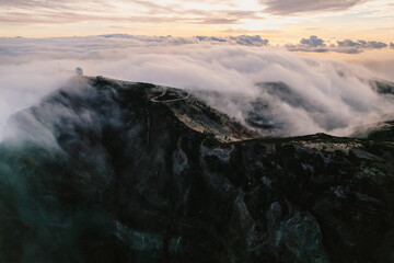 Aerial view of majestic mountain ridges at sunrise with falling fog from top of Pico do Areeiro, Madeira island, Portugal