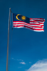 The Malaysian flag flying against a blue sky.