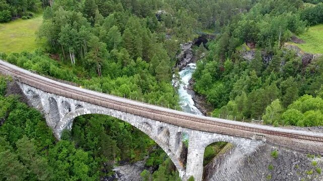 Aerial footage of Kylling Bridge, surrounded by lush forests and mountains, showcasing its architectural beauty and scenic surroundings.