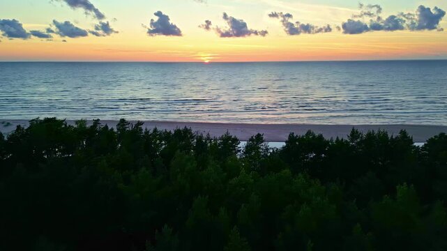 A panoramic view of the sunset over the Irbe River, with the dunes silhouetted in the foreground.