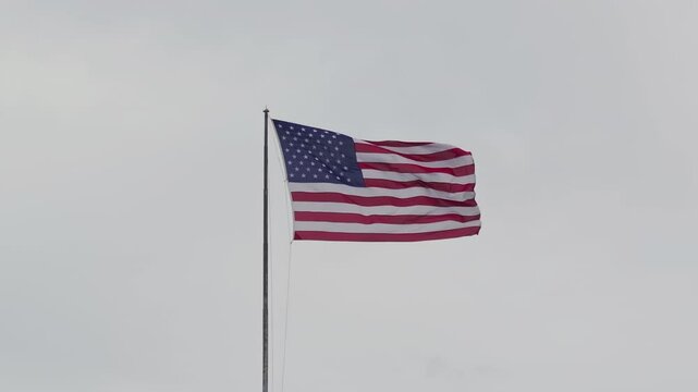 U.S. flag in slow motion under a cloudy sky