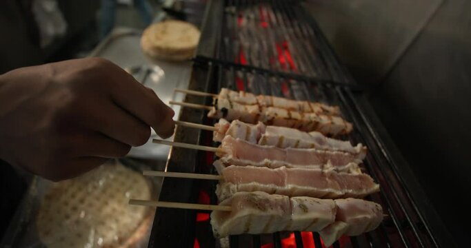 Close-up of a man's hand flipping grilled meat on a skewer. Strid food food and preparation of delicious meat. High quality 4k footage