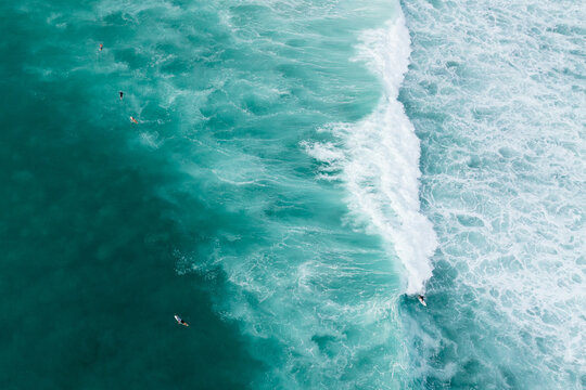 Drone shot of male short boarder surfing wave in Honolulu, Hawaii