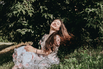 A beautiful woman is sitting on the grass and enjoying the sunshine