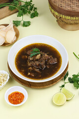 Rawon Daging Sapi or Indonesian beef black soup, traditional beef soup from East  Java, served with rice, bean sprouts, sambal, lime, and shrimp crackers.  