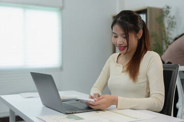 Young Asian businesswoman with creative colleagues working with laptop. Calculating.Financial management planning, analysis, startup project ideas, statistics and office investment markets.