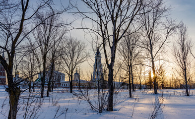 A snowy field with trees and a church in the background