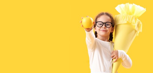 Happy little girl with school cone and fresh apple on yellow background with space for text