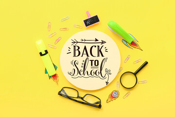 Creative composition with blank card, paper rockets and different stationery on yellow background