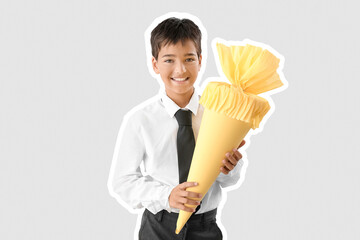 Little boy with yellow school cone on light background
