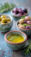 Fresh olives of different varieties displayed in small bowls, accompanied by a sprig of rosemary