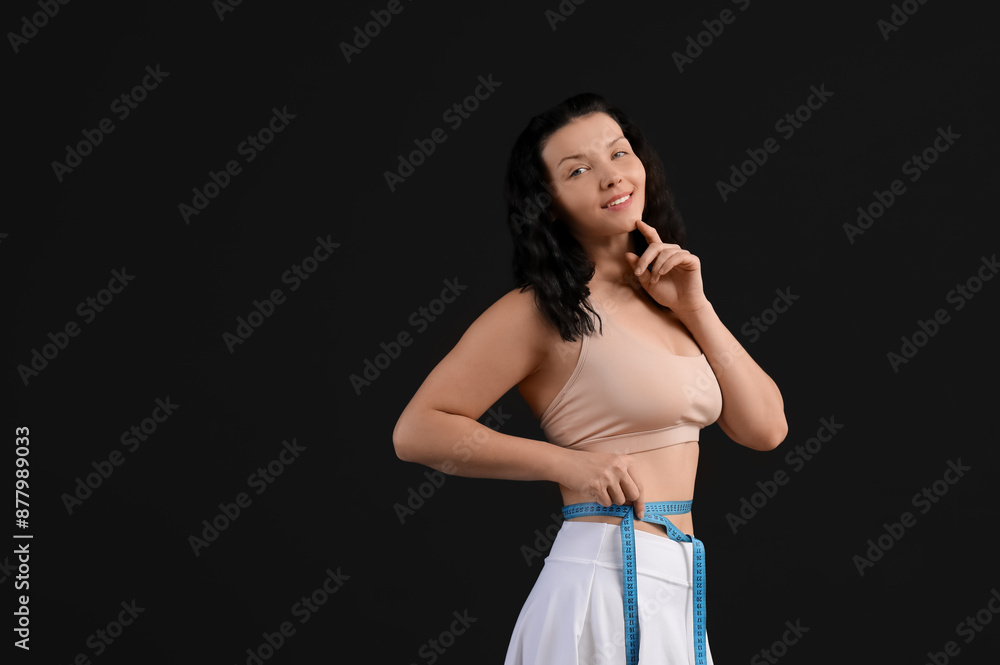 Sticker Beautiful young woman measuring her waist on black background. Weight loss concept