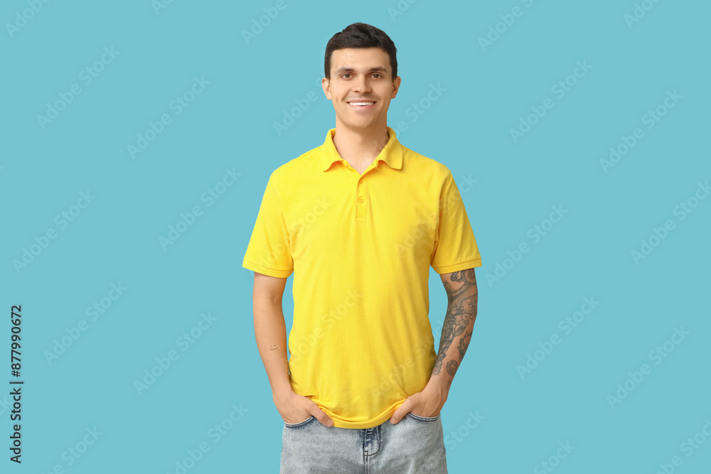 Wall mural Handsome young man in stylish yellow t-shirt on blue background