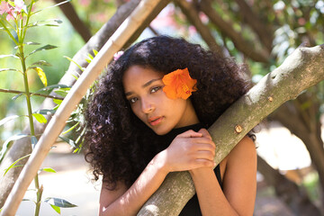 portrait of a beautiful young Latin woman with large, dark eyes and curly hair. The girl wears an...