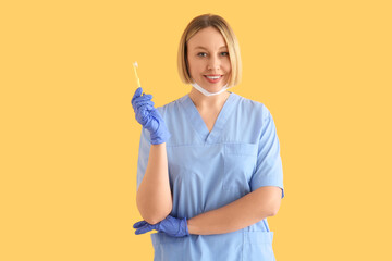 Female dentist with tooth brush on yellow background
