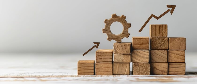Wooden blocks stacked in an upward trend with a gear on top and arrows symbolizing growth.