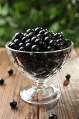 Ripe black currants in glass on wooden table, closeup