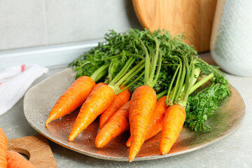 Tasty ripe juicy carrots on gray textured table, closeup