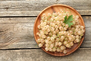 Fresh white currant berries and green leaf on wooden table, top view. Space for text