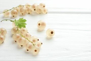 Fresh white currant berries and green leaf on white wooden table, closeup. Space for text