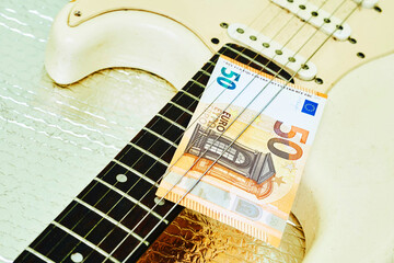 Fee. 50 euro banknotes on a rock electric guitar