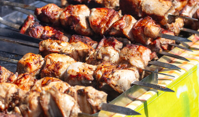 Meat is fried on skewers over coals on a grill