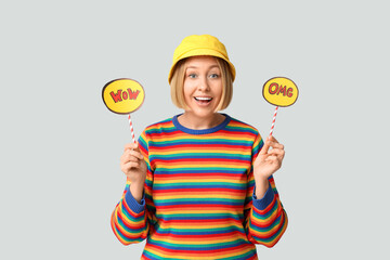 Surprised adult woman holding speech bubbles with words OMG and WOW on white background