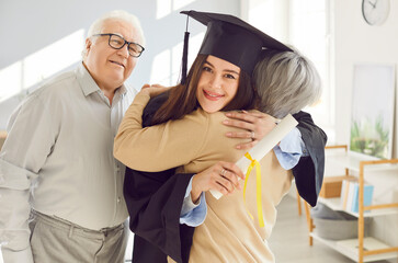 Portrait of a elderly parents congratulate daughter, a university graduate student in mortarboard...