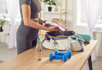 Woman is packing sports bag with essential items for fitness while going to sports training in gym....