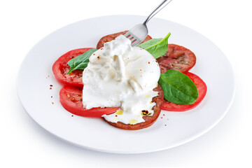 Burrata cheese with tomatoes and basil, on a plate on a white background. Fork with burrata cheese.