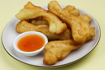 Cakwe or Youtio, popular Southeast and East Asian cuisine, made from Chinese dough and deep fry, savory taste served with chili sauce. Isolated background with copy space.
