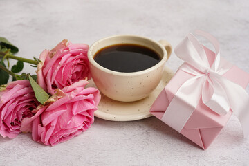 Gift box with beautiful roses and cup of coffee on white background