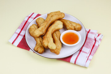 Cakwe or Youtio, popular Southeast and East Asian cuisine, made from Chinese dough and deep fry, savory taste served with chili sauce. Isolated background with copy space.