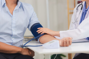 Fototapeta premium Female doctor uses digital blood pressure monitor Measuring blood pressure of male patient in hospital. Concept of medicine and health care.