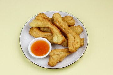 Cakwe or Youtio, popular Southeast and East Asian cuisine, made from Chinese dough and deep fry, savory taste served with chili sauce. Isolated background with copy space.