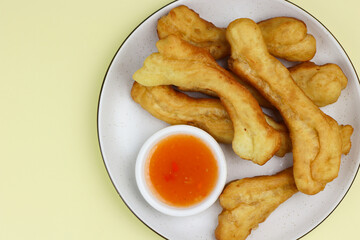 Cakwe or Youtio, popular Southeast and East Asian cuisine, made from Chinese dough and deep fry, savory taste served with chili sauce. Isolated background with copy space.